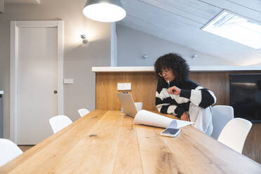 Thoughtful businesswoman looking at laptop in office - JAQF00986