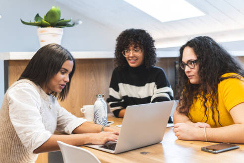 Junge Geschäftsfrauen schauen auf Kollegen, die in einem Coworking-Büro diskutieren - JAQF00993