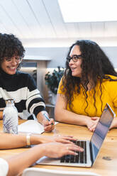 Smiling businesswomen discussing at coworking office - JAQF00995