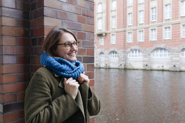 Smiling woman wearing warm clothing in front of wall - IHF00600