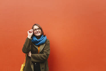Lächelnde Frau mit Brille vor einer orangefarbenen Wand - IHF00604