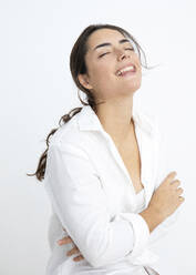 Smiling woman with eyes closed against white background - JBYF00043