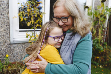 Lächelnde ältere Frau, die ihre Enkelin umarmt - IHF00608