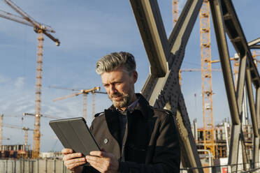 Geschäftsmann benutzt digitales Tablet auf einer Brücke - IHF00629