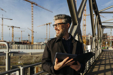 Lächelnder Geschäftsmann mit Tablet-PC auf einer Brücke - IHF00637