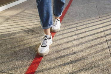 Woman walking on red marking at footpath - IHF00688