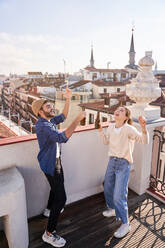 Ein Haufen fröhlicher Freunde, die lachend und tanzend auf einem Balkon in der Altstadt Bierflaschen in die Höhe halten - ADSF31965