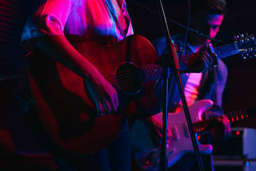 Mann spielt Gitarre, während eine Frau singt und ein Lied in einem Club mit Neonlichtern vorträgt - ADSF32085