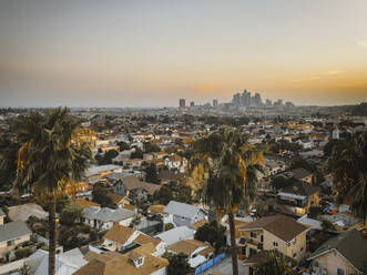 Luftaufnahme eines Wohngebiets in Kalifornien, Blick auf die Innenstadt von Los Angeles im Hintergrund bei Sonnenuntergang, Vereinigte Staaten von Amerika. - AAEF13492