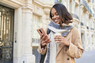 Young woman using mobile phone in city - KIJF04328