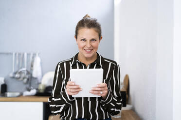 Lächelnde Geschäftsfrau mit digitalem Tablet in der Küche - GIOF14304