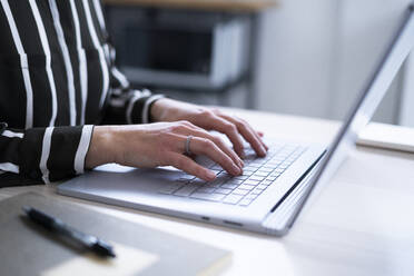 Businesswoman using laptop at home office desk - GIOF14309