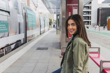 Young smiling woman at tram station platform - JRVF02088