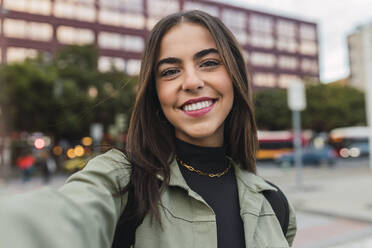 Lächelnde junge Frau nimmt Selfie in der Stadt - JRVF02118