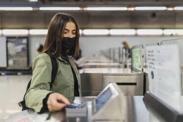 Frau mit Gesichtsmaske zahlt an Sicherheitsschranke in U-Bahn - JRVF02121