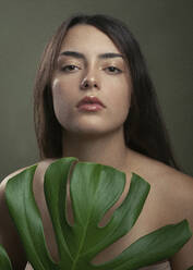 Shirtless young woman with monstera leaf - JBYF00048