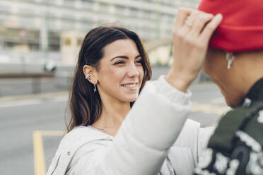 Smiling woman adjusting boyfriend's knit hat - MEUF04864