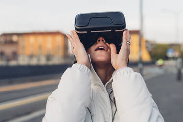 Junge Frau mit Virtual-Reality-Headset auf der Straße - MEUF04883