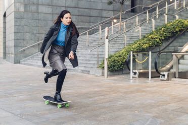 Geschäftsfrau auf dem Skateboard vor einem Bürogebäude - MEUF04936