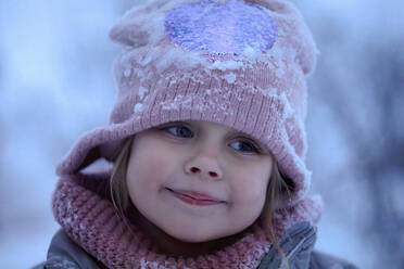 Niedliches lächelndes Mädchen mit Strickmütze und Schnee - ZEDF04300