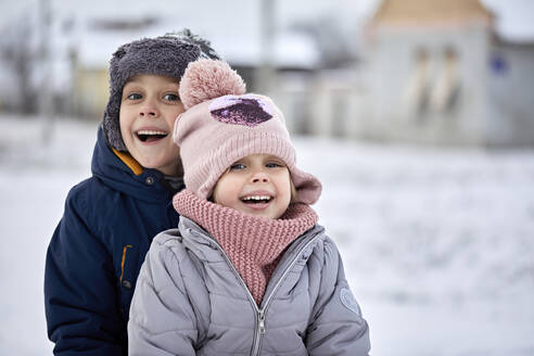 Fröhliche Geschwister in warmer Kleidung genießen gemeinsam den Winter - ZEDF04301