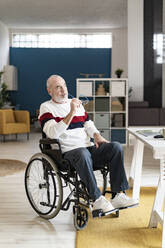 Nachdenklicher Geschäftsmann im Rollstuhl sitzend im Büro zu Hause - GIOF14333