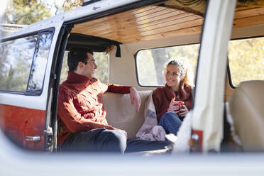 Smiling couple talking in campervan on weekend - EIF02444