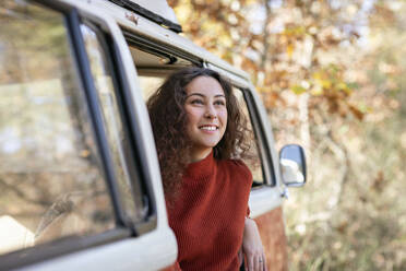 Lächelnde junge Frau, die vom Wohnmobil wegschaut - EIF02459