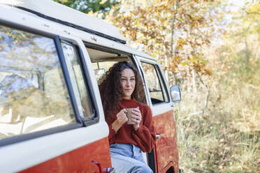 Young woman having coffee in compervan - EIF02462