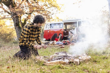 Mann brät Würstchen am Lagerfeuer im Herbstwald - EIF02466