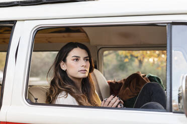 Young woman with coffee mug contemplating in motor van - EIF02482