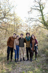 Smiling friends standing together in autumn forest on weekend - EIF02489