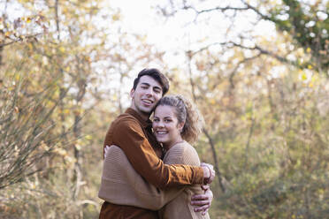 Smiling young couple hugging each other in autumn forest - EIF02495