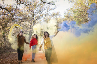 Fröhliche Freunde haben Spaß mit Rauchfackeln im Herbstwald am Wochenende - EIF02497