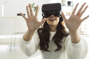 Woman using virtual reality headset at home - JCCMF04702