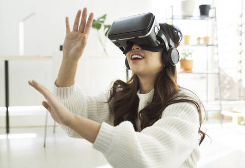 Young woman using virtual reality headset at home - JCCMF04703