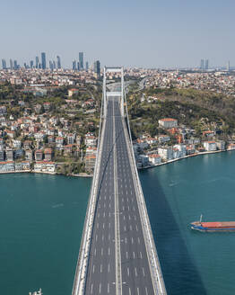 Luftaufnahme eines Containerschiffs, das im Marmarameer unter der Patih Sultan Mehmet Koprusu-Brücke in Istanbul, Türkei, hindurchfährt. - AAEF13507