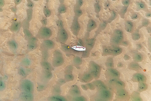 Aerial view of a small sailing boat in River Camel during low tide, Rock town, Cornwall, United Kingdom. - AAEF13510