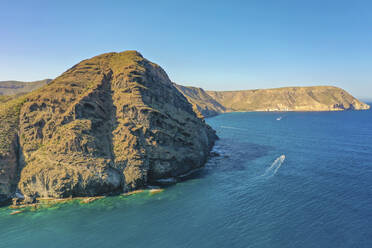 Luftaufnahme eines Naturschutzgebiets in Cerro Negro neben einer felsigen Küste und einem davonfahrenden Boot in der Provinz Almería, Andalusien, Spanien. - AAEF13567