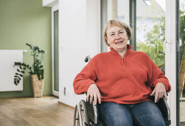 Lächelnde behinderte Frau im Rollstuhl zu Hause - UUF25102
