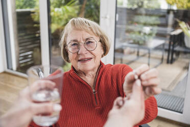 Care assistant giving medicine to senior disabled woman at home - UUF25118