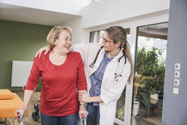 Junger Arzt hilft einer behinderten Frau, zu Hause aufzustehen - UUF25122