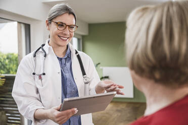 Doctor with tablet PC talking to senior patient at home - UUF25128