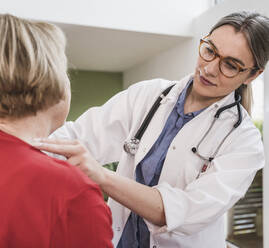 Mitarbeiter des Gesundheitswesens bei der Kontrolle des Halses eines Patienten zu Hause - UUF25131