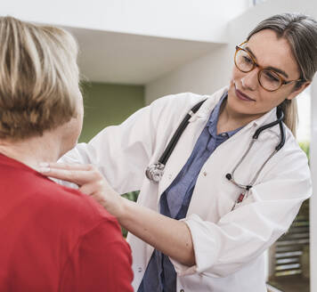 Mitarbeiter des Gesundheitswesens bei der Kontrolle des Halses eines Patienten zu Hause - UUF25131