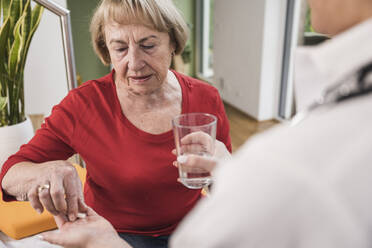 Ältere Frau nimmt zu Hause Medikamente vom Arzt ein - UUF25135