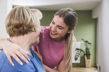 Young physiotherapist with hand on woman's shoulder at home - UUF25153