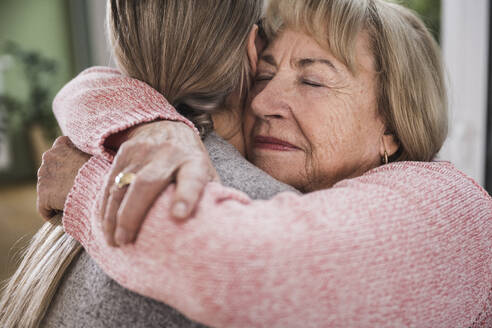 Senior woman hugging caregiver at home - UUF25172