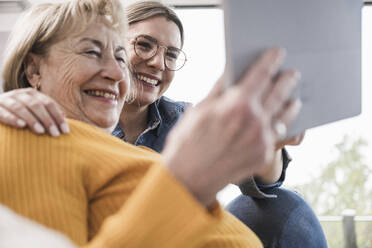 Lächelnde Frauen, die zu Hause einen Tablet-PC benutzen - UUF25185