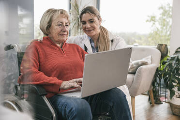 Behinderte Frau benutzt Laptop mit Krankenschwester zu Hause - UUF25200